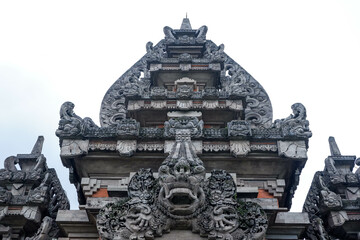 Front view of a traditional Balinese Hindu temple gate with intricate stone carvings and sacred...