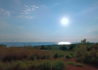 Obraz premium A breathtaking scene unfolds as the sun sets beyond the ocean, its golden light gently reflected on the sea, viewed from a quiet mountain ridge in Bataan, Philippines