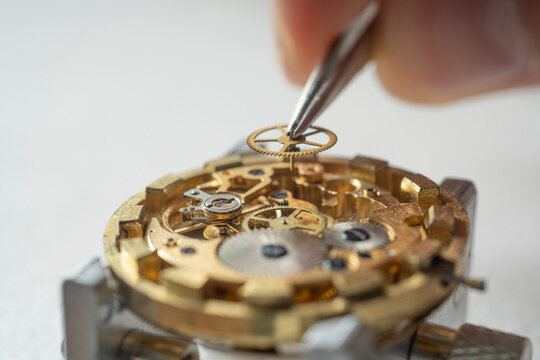 Professional watchmaker repairer working on an old vintage pocket watch in a workshop.
