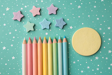 Pastel colored pencils and stars on teal background