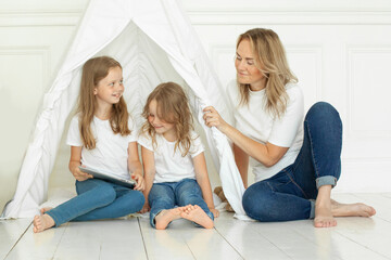 Obraz premium Happy mother and two daughter. Family using tablet gadget at home