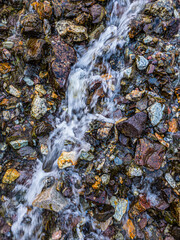 Serene stream flowing over colorful rocks in nature