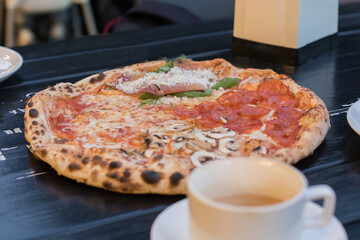 Delicious pizza served at an outdoor cafe with a warm beverage