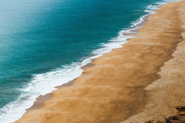 Naklejka na ściany i meble Aerial view of a deserted beach with turquoise waves.
