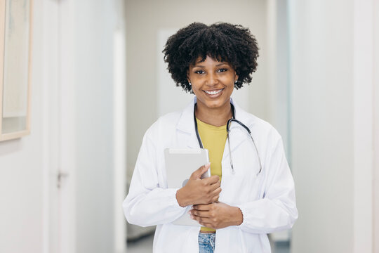 Smiling female doctor holding digital tablet in hospital corridor