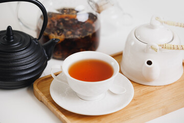 Elegant tea setting with black ceramic kettle and white teapot on wooden tray