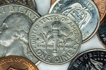 One dime US Dollar on top of different currency coins on white background macro