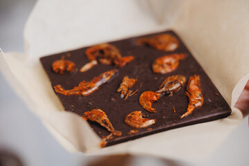Unique dark chocolate with dried shrimps on parchment paper