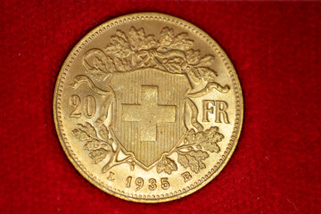 Swiss gold coin quarter ounce pure gold macro on red background