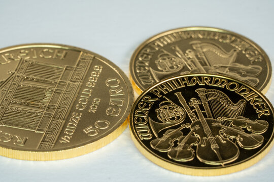 Three gold ounce coins Krugerrand Wiener Philharmoniker pure gold on white surface 1