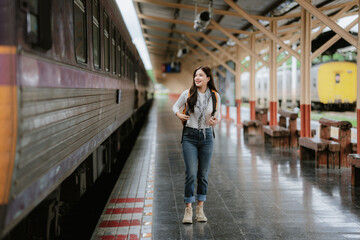 A pretty Asian female tourist walking in a train station.