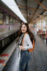 A beautiful Asian female tourist smiling while using her phone at a train statio