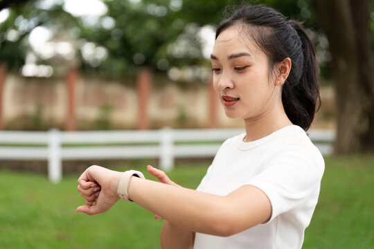 Fitness and Wellness. Young woman checking smartwatch while preparing for outdoor exercise.