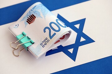 Israel New Shekels banknotes on national flag. The current Israel money bills lies on flag in big...