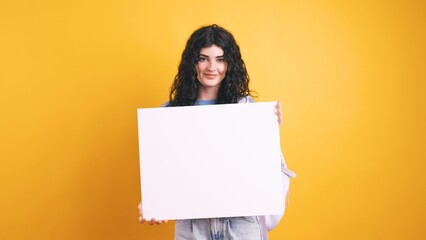 Smiling student showing white blank board on yellow background