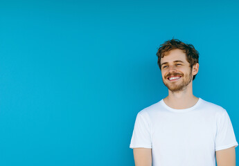 Excited Man in White T-Shirt and Jeans Pointing Left – Advertising Banner Mockup, Blue Background, High-Resolution Stock Photo for Marketing & Promotional Designs