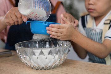 Family Bonding through Cooking. A mother and son measuring sugar together in the kitchen.
