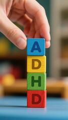 A hand stacking colorful blocks spelling "ADHD"