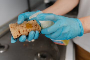 Close-up hands of unrecognizable person squeezing detergent onto sponge, getting ready to cleaning...