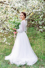 A beautiful girl in an elegant white dress with long sleeves and a transparent back, in the boho...