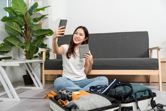 Selfie Moment and Travel Preparation. Young woman taking a selfie while packing her suitcase.