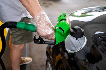 Man driver hand refilling and pumping gasoline oil the car with fuel at he refuel station. Car refueling on petrol station. 