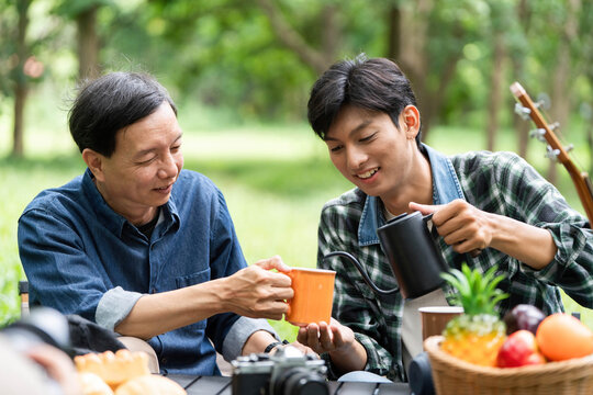 Family bonding outdoors. A father and son sharing drinks and laughter in nature.
