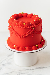 Delicate lambeth style birthday cake with red cream cheese frosting decorated with cream tracery...