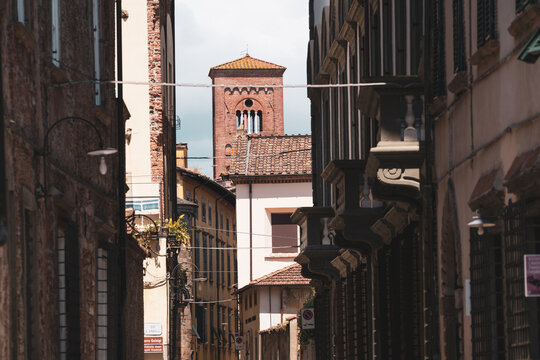 Fototapeta Narrow street in old Italian town with view of historic brick bell tower and traditional buildings.
