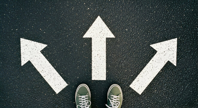 Overhead view of three white arrows on dark asphalt, pointing different directions, with feet in the center