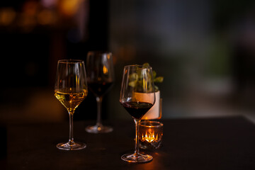 Elegant wine glasses with red and white wine on a dark table with candlelight, creating a cozy and romantic atmosphere in a fine dining setting.