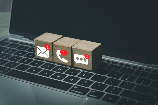 Wooden blocks with new notification icons for email, phone call, and message on a laptop. Concept for business communication, customer support, contact center,email notifications.