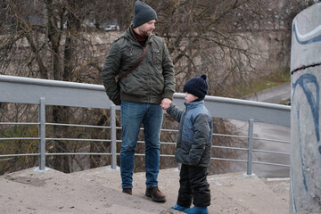 Father and son walking down on sidewalk together. Portrait of a handsome middle-aged man with...