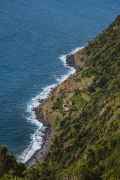 View of Faja do Araujo, a Remote Coastal Settlement on a Steep Azorean Cliffside. Sao Jorge, Azores. Lush Vegetation, Atlantic Ocean crashes below, Terraced Fields