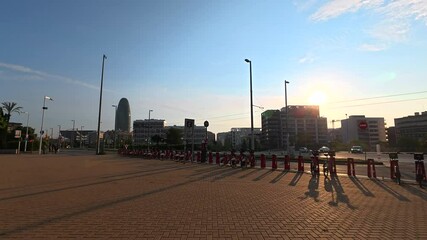 Golden sunlight bathing parked electric scooters near iconic agbar tower, capturing barcelona's urban morning landscape with warm, vibrant colors and innovative mobility infrastructure