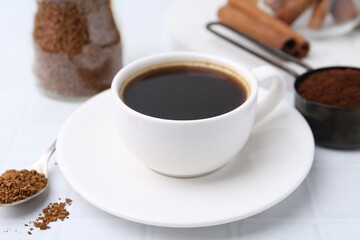Cup of aromatic coffee and instant powder on white table, closeup