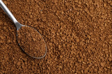 Spoon on aromatic granulated instant coffee, top view. Space for text