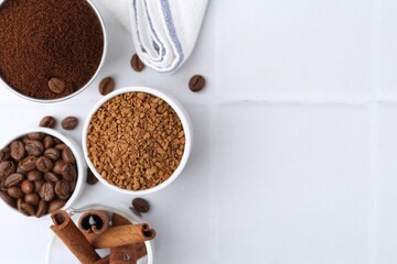 Different types of instant coffee, beans and cinnamon sticks on light tiled table, flat lay. Space...