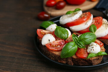Tasty sandwiches with mozzarella cheese, tomatoes, basil and spices on wooden table, closeup. Space for text