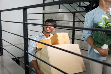 Cheerful gay couple moving boxes into their new home, smiling together