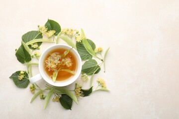 Fresh linden tea in cup and flowers on white table, flat lay. Space for text
