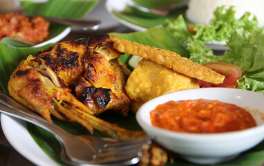 Grilled chicken served with steamed rice, crispy fried tempeh and tofu, and spicy chili sambal—an authentic and fiery Indonesian meal