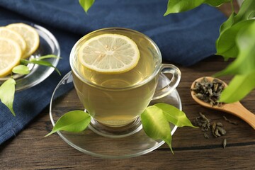 Refreshing green tea with lemon and leaves on wooden table, closeup