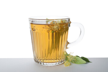 Tasty linden tea in cup, leaves and flowers isolated on white