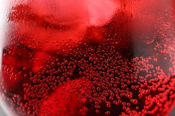 Glass of tasty cherry soda with ice cubes and berry as background, closeup