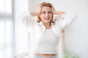 Stressed mature woman with headache at home