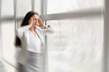 Young businesswoman suffering from headache in office