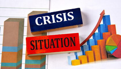 CRISIS SITUATION - words on multi-colored wooden blocks on the background of charts
