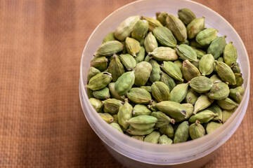 A bowl of fresh green cardamom seeds arranged on a table for use or display