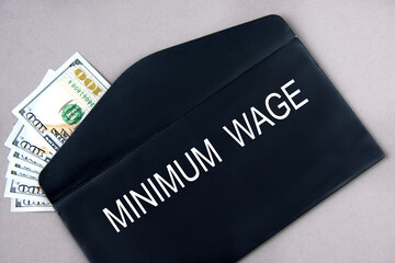 MINIMUM WAGE - words on a black envelope with banknotes